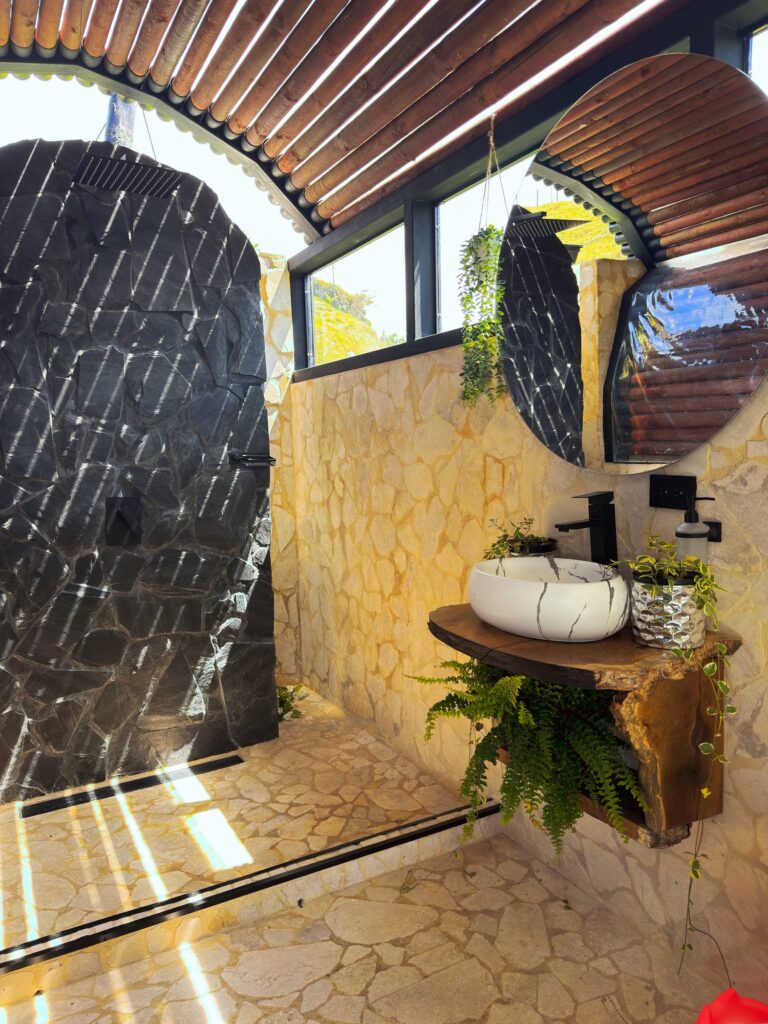 Baño de piedra con ducha tipo lluvia en la cabaña Venus